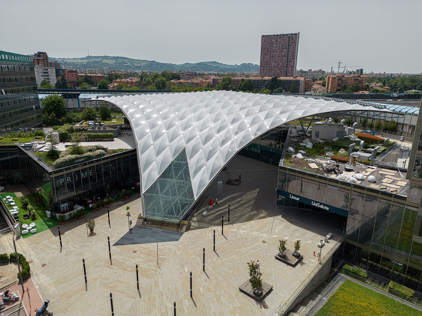 Large tensile architectural fabric roof structure covering an urban public space in Bologna.